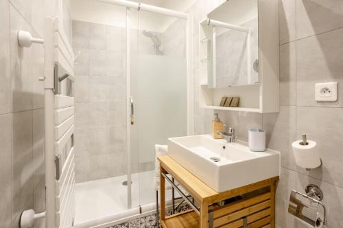 une salle de bain blanche avec un lavabo et une douche dans l'établissement Appartement cosy proche Beaubourg, à Paris
