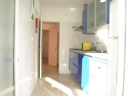 uma cozinha com armários azuis e brancos e um lavatório em Caparica Beach House em Costa da Caparica