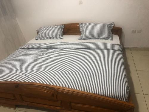 a bed with a wooden frame and two pillows on it at WILLS COURT in Accra