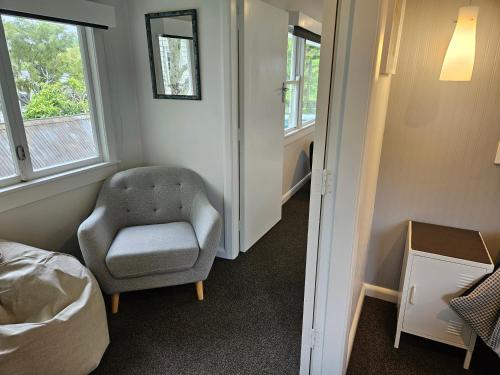 a room with a chair and a bed and windows at Inner city base in Nelson