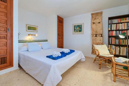 a bedroom with a bed and a chair and a book shelf at Olivo in Jávea