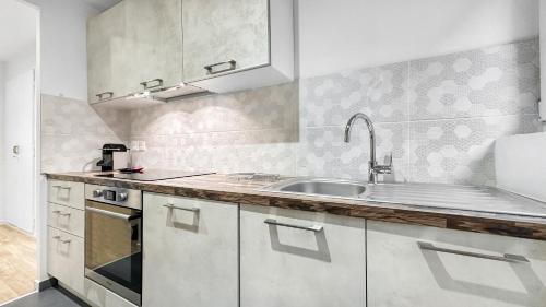 une cuisine avec des armoires blanches et un évier dans l'établissement COLOC PASTEUR - Belle colocation de 3 chambres - Hypercentre - Proche Gare et Tram - Wifi gratuit, à Annemasse