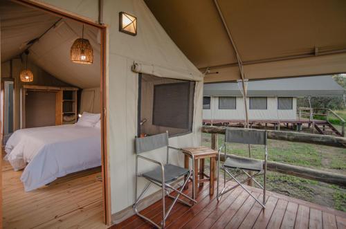 a bedroom with a bed and chairs in a tent at Nkambeni Safari Camp in Hazyview