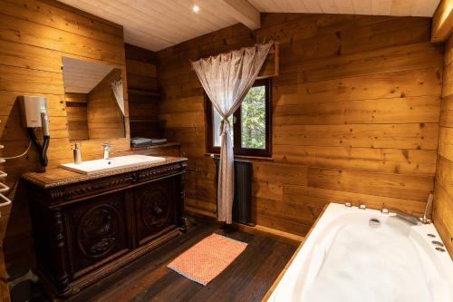a wooden bathroom with a tub and a sink at Le refuge du peintre in Gérardmer