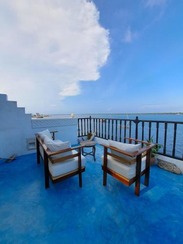a balcony with chairs and a table and the ocean at Pwani House - Lamu Seafront in Lamu
