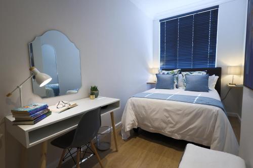 a bedroom with a bed and a desk and a mirror at 505 La Roche, Paarl in Paarl