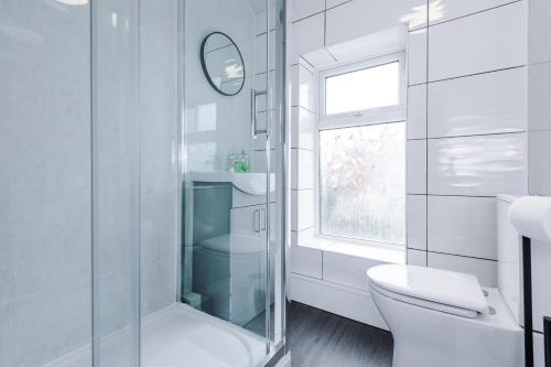 a white bathroom with a toilet and a window at Creative Cottage 4 BR PrimeStay in Bolton