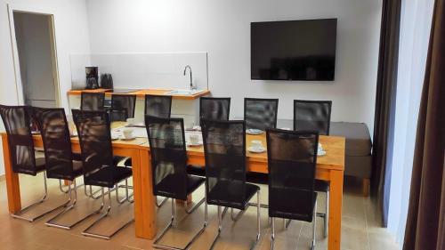 a dining room table with black chairs and a television at Eleonoras Ferienwohnungen in Würzburg Stadt inklusive eigenen Parkplätzen vor der Tür in Würzburg