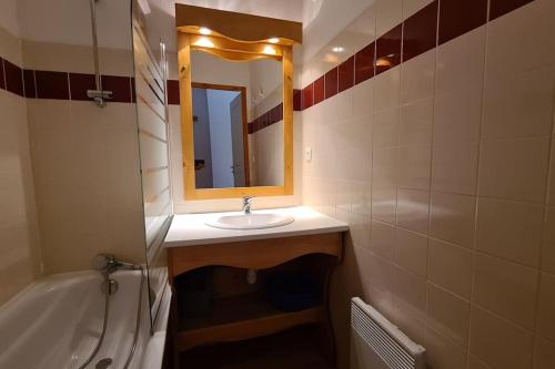 ein Badezimmer mit einem Waschbecken, einem Spiegel und einer Badewanne in der Unterkunft Chamrousse, 50m piste, wifi +, terrasse vue sapins in Chamrousse
