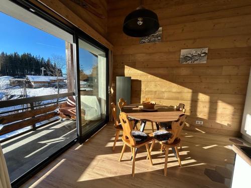 Ce chalet en bois dispose d'un balcon avec une table et des chaises. dans l'établissement Appartement le StelO Les Gets 6 personnes aux pieds des pistes 2 chambres, aux Gets