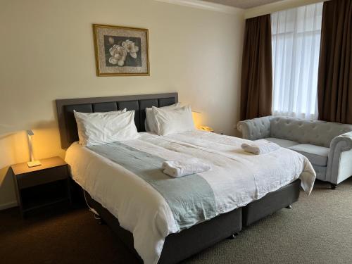- une chambre avec un grand lit et un canapé dans l'établissement Best Western Governor Gipps Motor Inn, à Traralgon