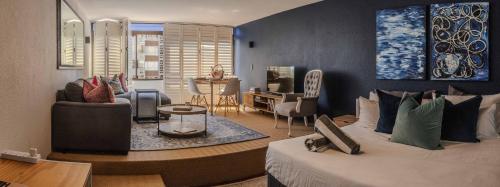 Studio Blue in Mouille Point في كيب تاون: غرفة نوم مع سرير وغرفة معيشة
