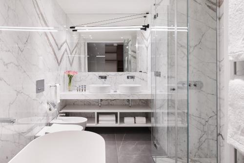 a white bathroom with two sinks and a shower at Hotel Belvedere in Bellagio
