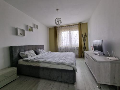 a bedroom with a bed and a dresser and a window at Gray apartment nearby Amethyst & Vivo Mall in Floreşti