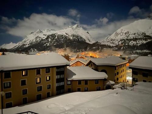 a city with snow covered buildings and mountains in the background at Ferienwohnung Residenza Chesa Margun 34-5 in Surlej