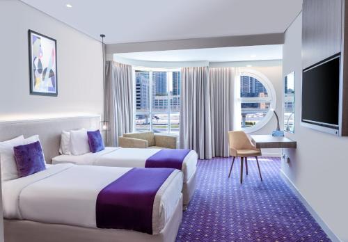 a hotel room with two beds and a tv at Leva Hotel and Suites, Opposite Downtown in Dubai