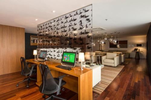 Brasil 21 suite flat في برازيليا: غرفة بها مكتب وبه جهاز كمبيوتر وكراسي
