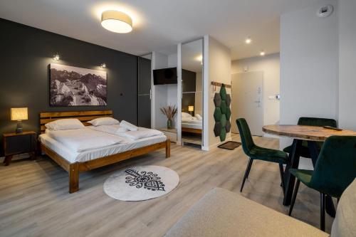 Un dormitorio con una cama y una mesa y sillas. en RentPlanet - Apartamenty Zakopiańskie II, en Zakopane