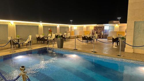 فندق شيرفل الواحة عنيزة Cheerful Al Waha Unayzah Hotel في عنيزة: مسبح بالطاولات والكراسي في الفندق