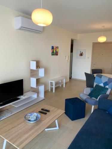 a living room with a blue couch and a table at PALLINIO COURT 402 Fig Tree Bay- Protaras Beach, IASONOS STR 7A in Protaras