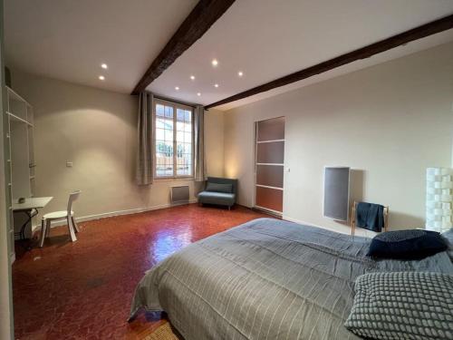 Appartement spacieux et calme à Aix en Provence في آكس أون بروفانس: غرفة نوم بسرير وكرسي ومكتب