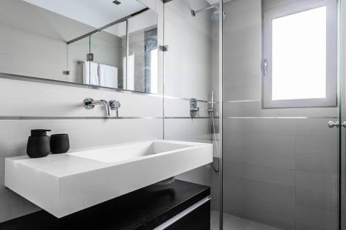 a white bathroom with a sink and a mirror at 3 Bed luxury apartment with pool in Glyfada in Athens