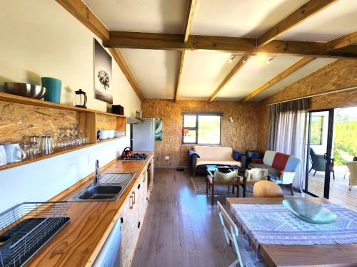 a kitchen with a sink and a living room at Caracal Cottage in Plettenberg Bay