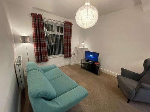 ein Wohnzimmer mit einem blauen Sofa und einem TV in der Unterkunft Hillview House in Belfast