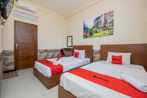 een slaapkamer met 2 bedden met rode en witte lakens bij RedDoorz Syariah near Batu Night Spectacular in Malang