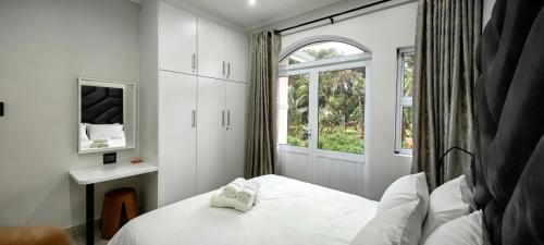 a small bedroom with a bed and a window at Caribbean Estates Villa Varie - Luxury accommodation in Port Edward