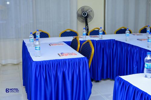 um grupo de mesas com corredores de mesa azuis e garrafas de água em Hotel Cavallino em Kakamega