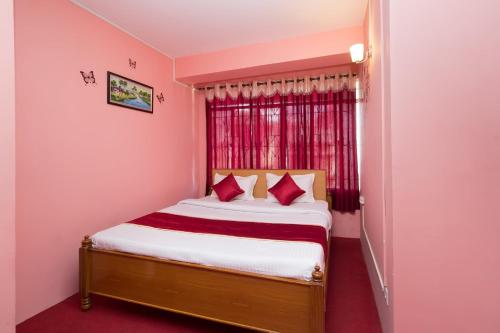 een kleine slaapkamer met een bed met rode gordijnen bij OYO Flagship Balaji Guest House in Shillong