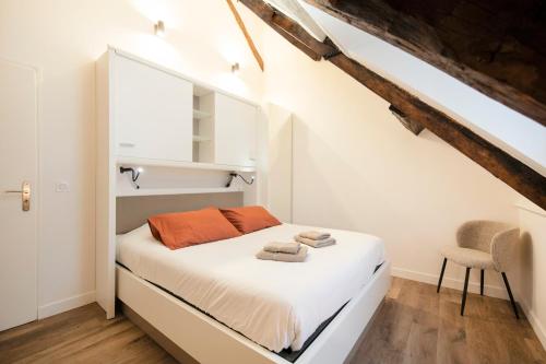 Un dormitorio con una cama blanca con almohadas naranjas. en Le Laurencin Sens - Le Family en Sens