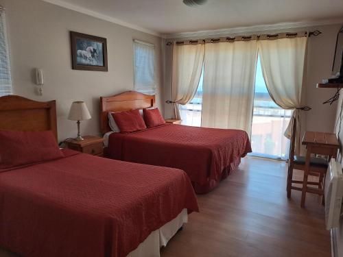 a hotel room with two beds and a window at Hotel Solaris in Huasco