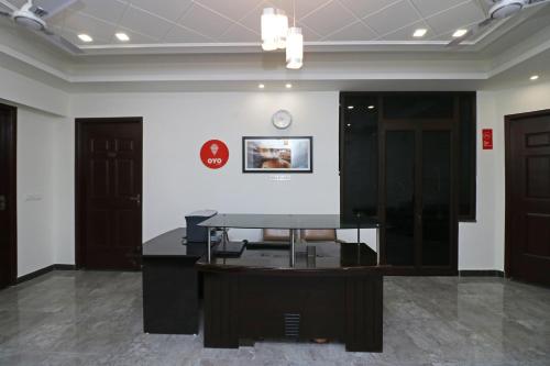 a glass table in a room with a clock on the wall at Jagat Residency in Rājpur