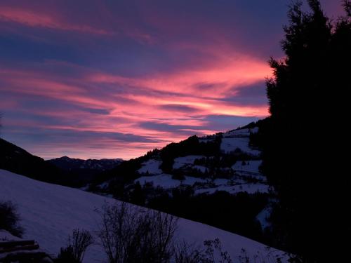 a sunset over a snow covered mountain with trees at Casa Picca & Lotta in Radenthein