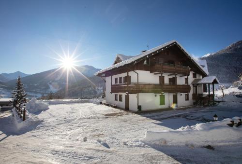 Una casa en la nieve con el sol detrás. en Residence Fior d'Alpe, en Valdidentro