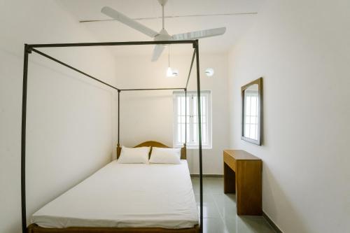 a bedroom with a four poster bed with a ceiling fan at Dias Legacy Bungalow in Talpe