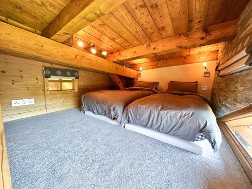 two beds in a room with wooden ceilings at Chalet Flocon - luxury ski chalet by Avoriaz Chale in Avoriaz