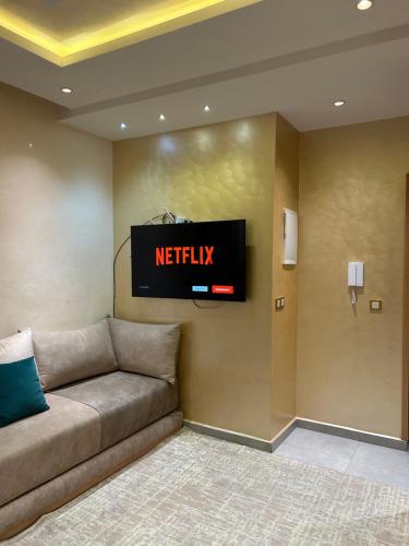 a couch in a room with a television on a wall at Appartement Gold moderne avec hammam centre ville in Agadir