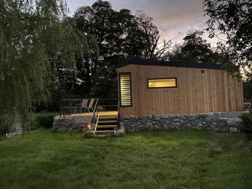a tiny house with a stone wall and a window at The Lily Pod in New Abbey