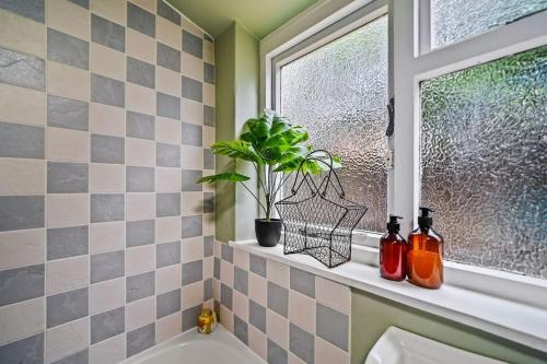uma casa de banho com uma janela e uma planta numa saliência em Micawber Cottage, Rattlesden em Rattlesden