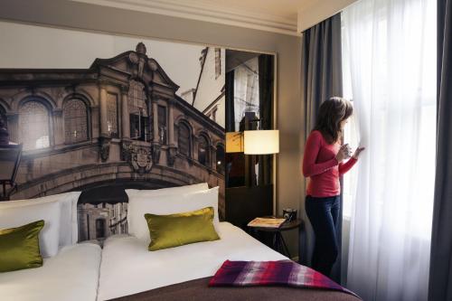 a woman looking out the window of a hotel room at Mercure Oxford Eastgate Hotel in Oxford