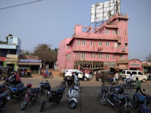 een groep motorfietsen geparkeerd voor een roze gebouw bij Hotel Ashray,Bhubaneswar in Bhubaneshwar