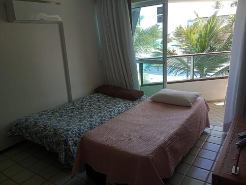ein kleines Schlafzimmer mit einem Bett und einem Fenster in der Unterkunft Resort Ancorar Porto de Galinhas Flat 1202 in Porto De Galinhas