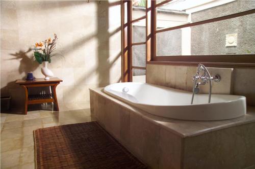 a bathroom with a bath tub with a window at Villa Stefan in Pantai Anyer