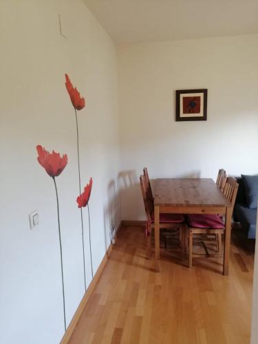 a dining room with a wooden table and two red flowers at Ainsa in Aínsa