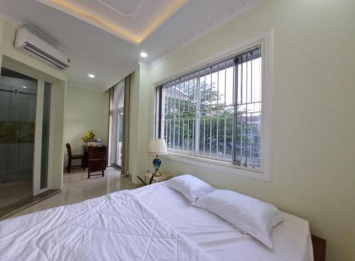 a bedroom with a white bed and a large window at Bếp Ông Tỏi Homestay in Ho Chi Minh City