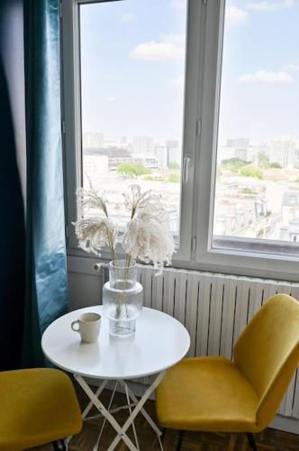 d'une table avec deux chaises et d'un vase avec des fleurs. dans l'établissement Super studio tout équipé - III, à Paris