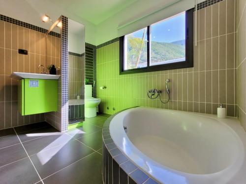 a green bathroom with a tub and a window at Miya del Sol Heated Saltwater Pool in La Orotava